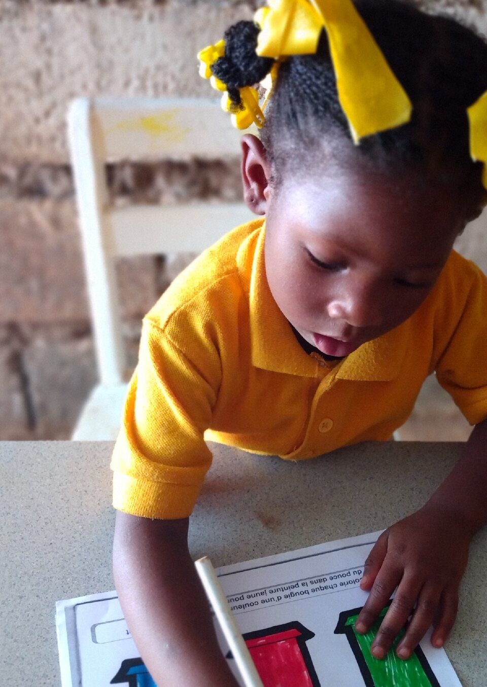 An early childhood student in Southern Haiti colors a classroom worksheet.